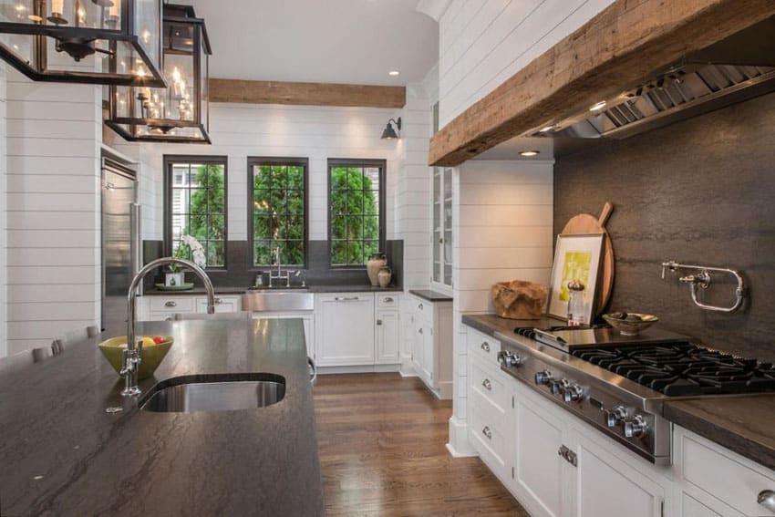Country kitchen with white cabinets shiplap board walls and black soapstone countertops