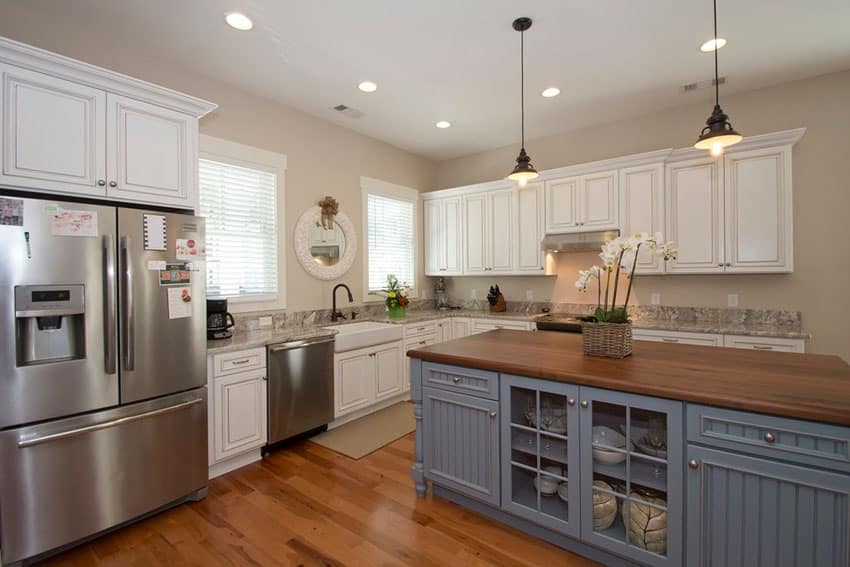 Country kitchen with white cabinets walnut countertop, painted blue island and farmhouse sink