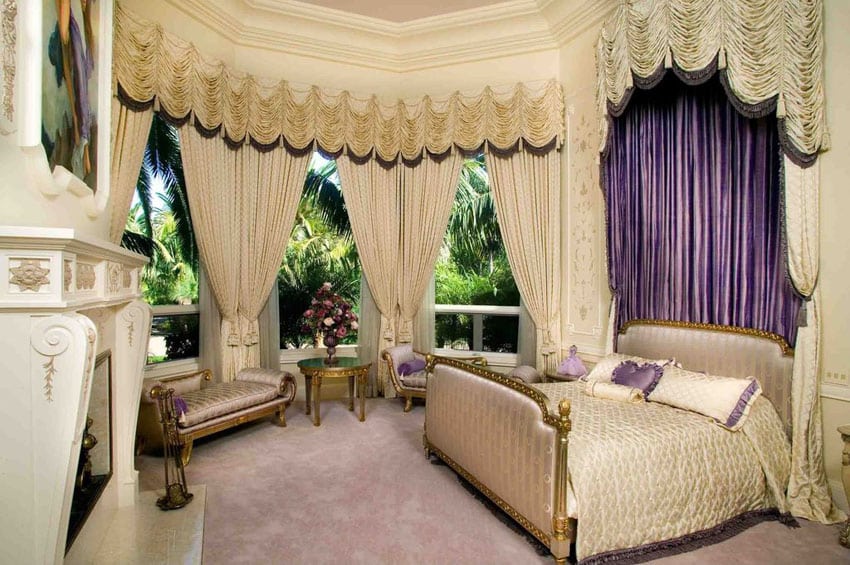 Gorgeous bedroom with gilded gold bed frame, bed drapery, large windows, gold furniture pieces and fireplace