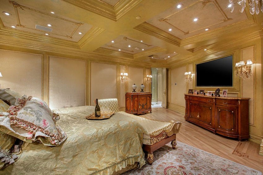 Luxurious master bedroom with gold decor, chaise lounge and rich wood furniture