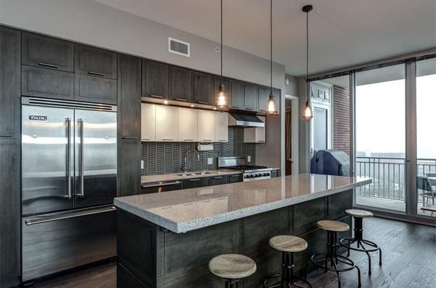 Kitchen with rich dark wood cabinets with European pull hardware and Edison style pendant lights 