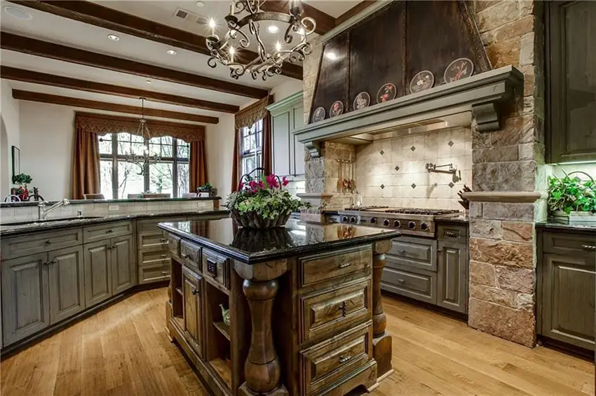 Luxury traditional kitchen with raised panel dark cabinets with antique black granite counter stone oven surround and island