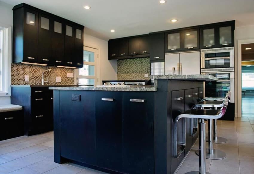 Modern kitchen with black glass cabinets, two tier island, bar stools and glass backsplash