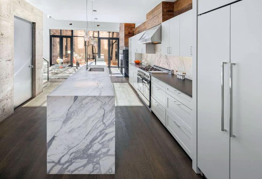 Contemporary kitchen with marble clad waterfall island and white cabinets
