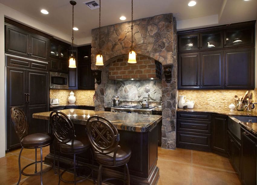 Kitchen with dark wooden chairs, travertine tiles, and stacked stone backsplash