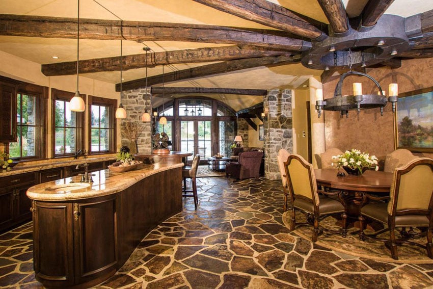 Rustic kitchen with rounded island topped with colonial cream granite and 12 light wrought iron chandelier