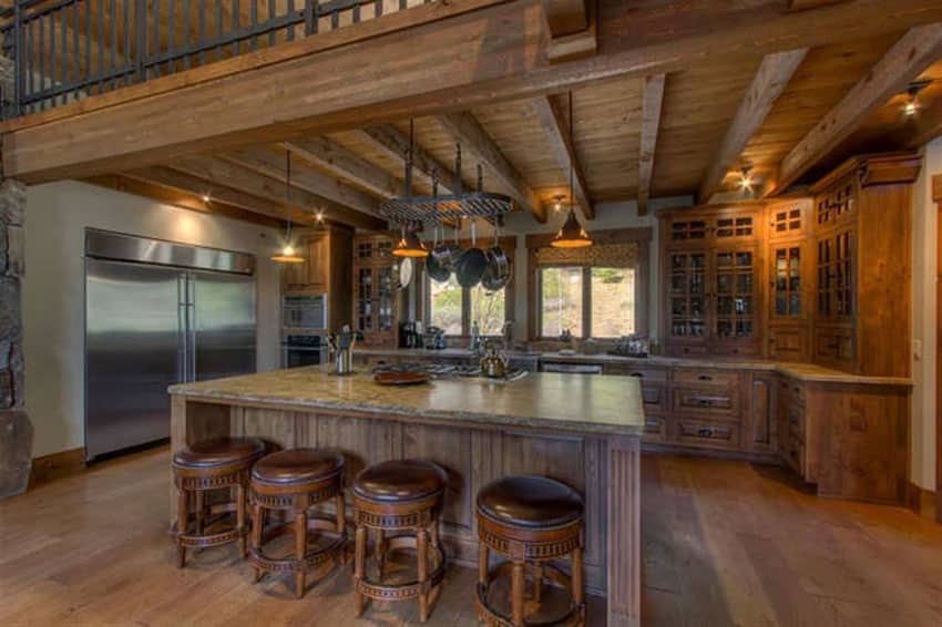 Rustic kitchen with wood beams below balcony and large rectangular island