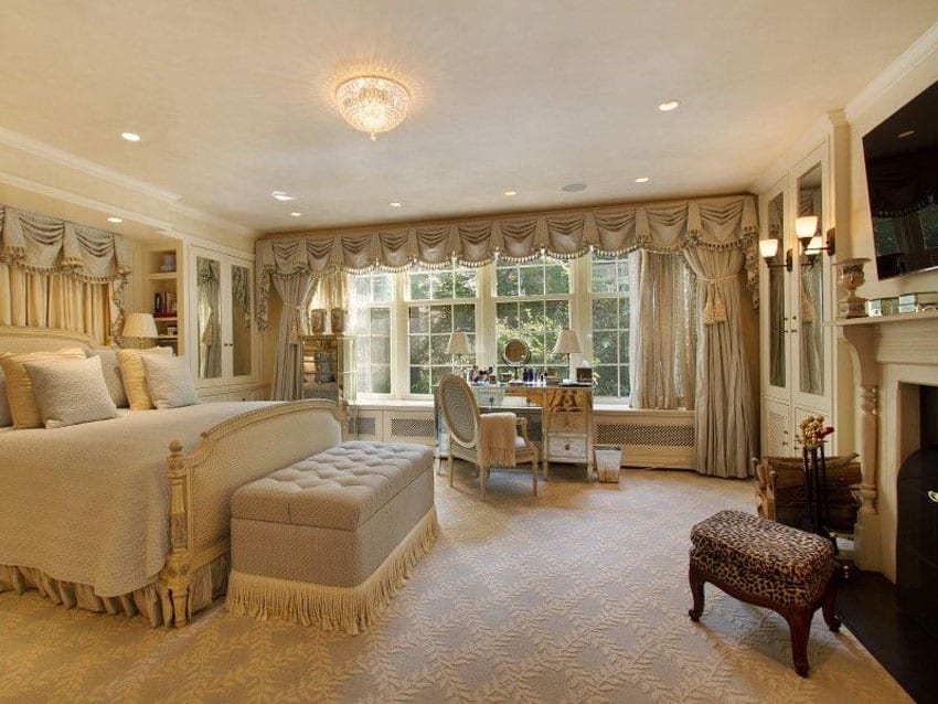 Traditional master bedroom with bed ottoman and fireplace