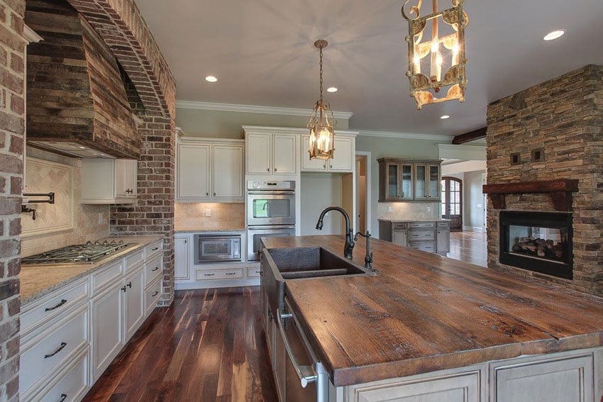 Traditional kitchen with rustic white cabinets, butcher block island and lantern style pendant lighting