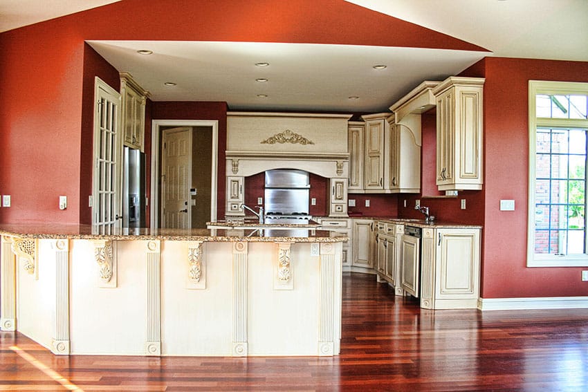 Traditional kitchen with painted cream color decorative cabinetry, granite peninsula and red walls