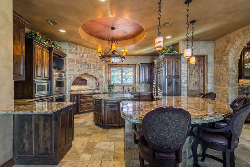 Traditional kitchen with rustic cabinets, cupola ceiling with wrought iron chandelier and curved breakfast bar granite island