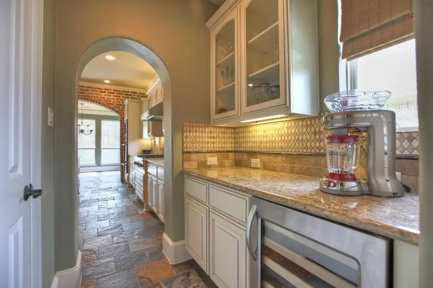 Kkitchen with arched doorway, mixer on countertop and stone floors