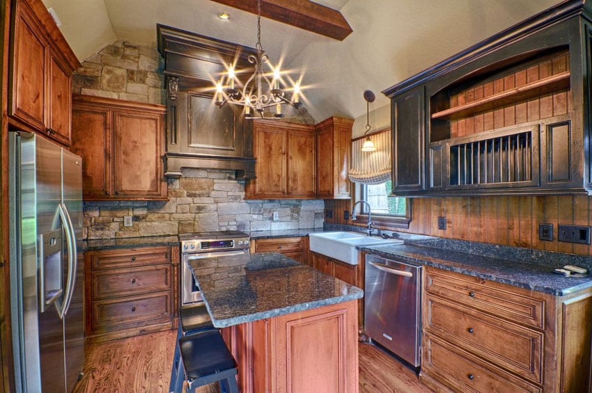 U shaped country kitchen with rustic cabinets, steel grey granite countertops and rough cut stone accent walls