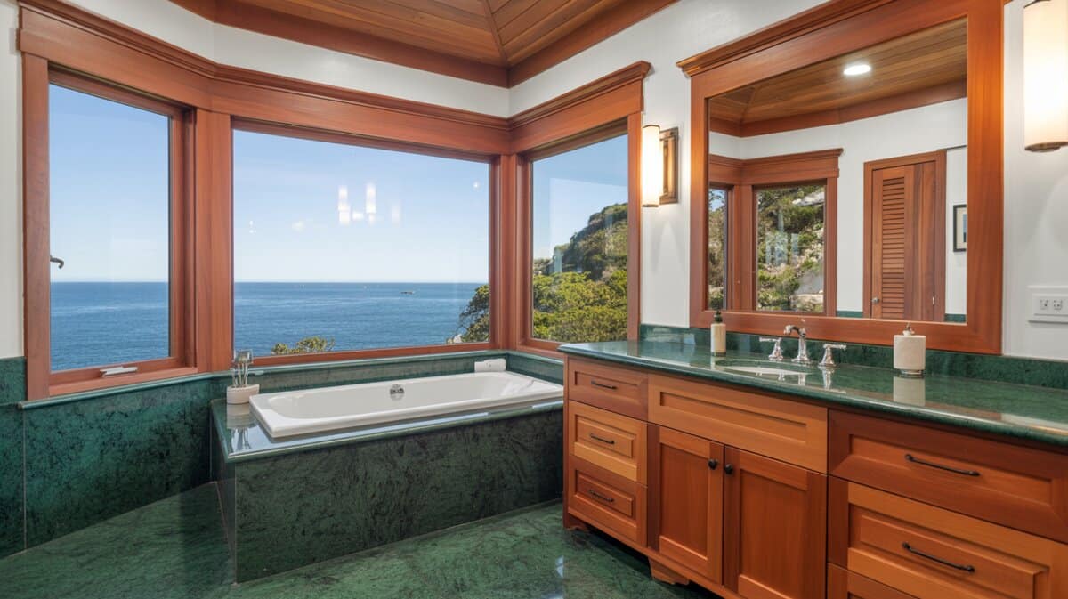 Drop-in tub and green marble vanity overlooking a blue ocean view