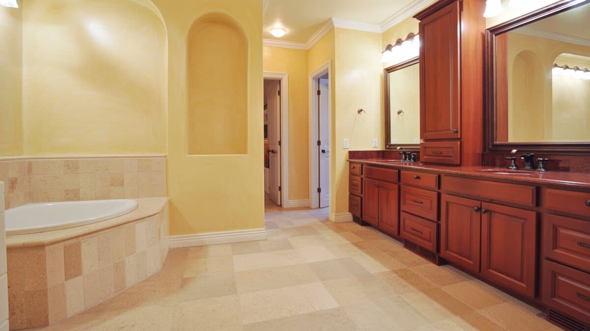 Cherry vanity with red granite counters against soft butter yellow walls