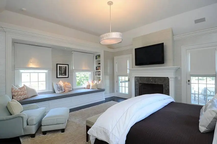 Bedroom with drum pendant light, TV above the mantle and fireplace