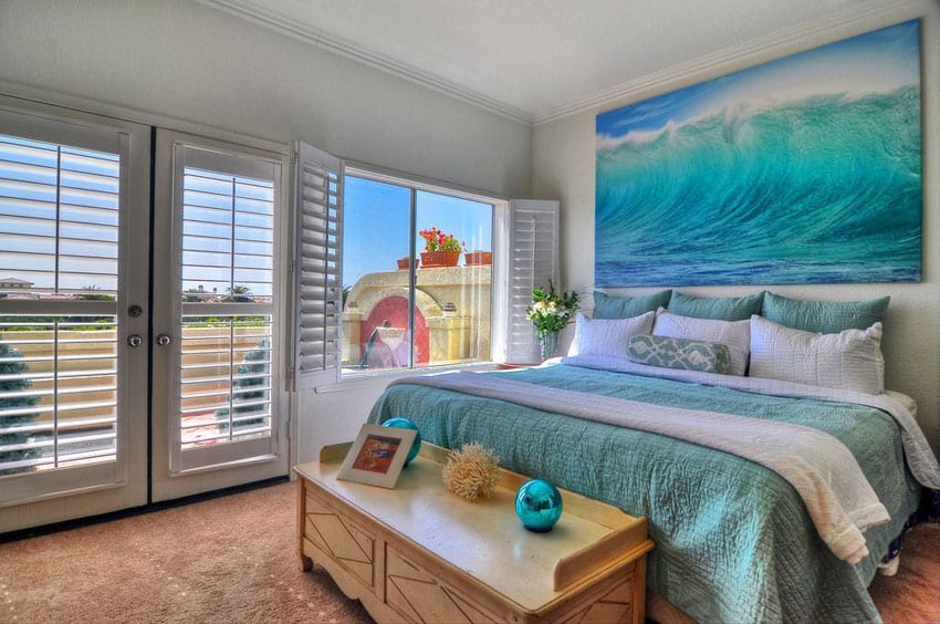 Bedroom with ocean wall art, teal bed covers and white plantation shutters