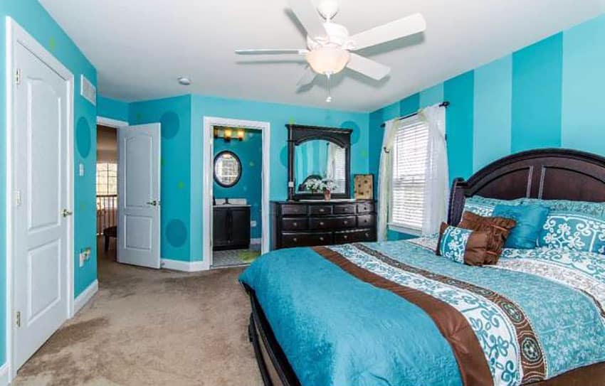 Bedroom with striped teal walls with circular designs