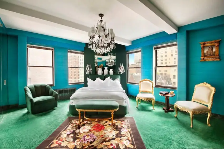 Bedroom with teal walls, chandelier and green carpet