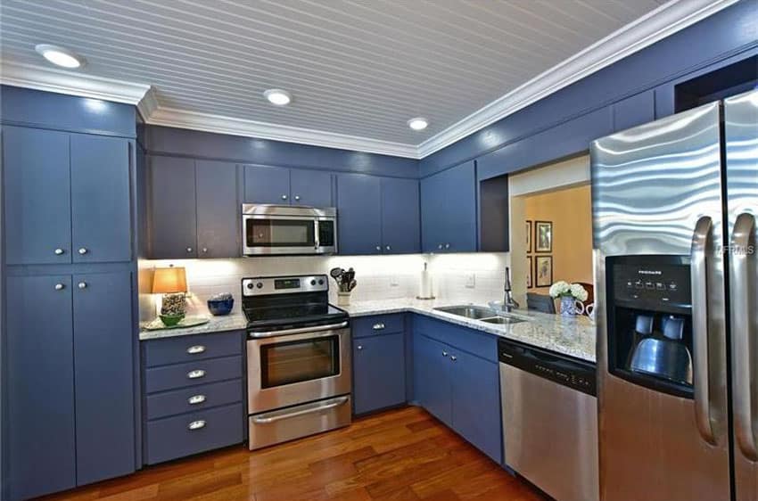 Blue cabinet kitchen with white moldings and blanco tulum granite counters