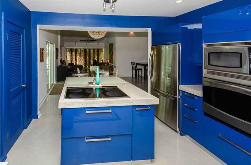 Kitchen with cobalt blue walls, concrete counters and baseboard