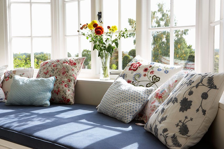 Window with floral cushions and flower vase