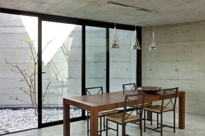 Concrete walled room with walnut table and glass lights