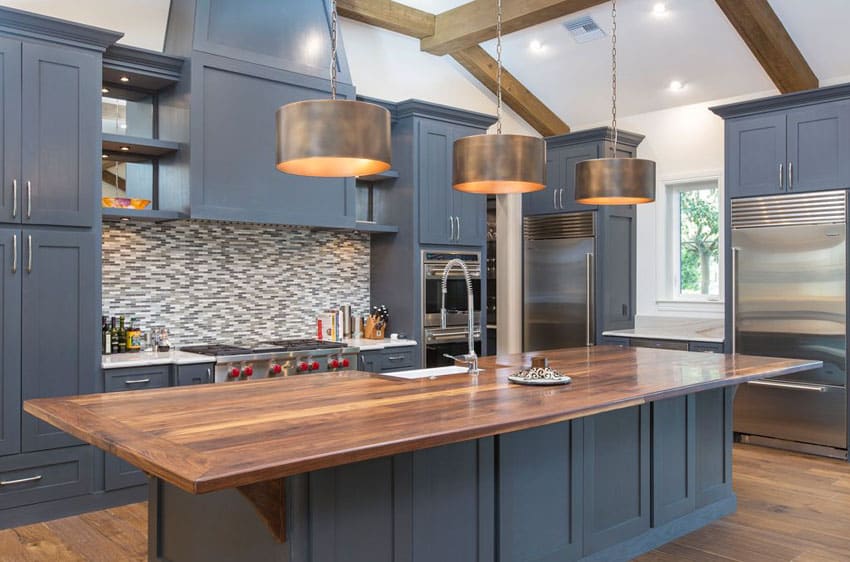 Kitchen with dark blue cabinets, chef's block counters and bronzed drum pendant lights