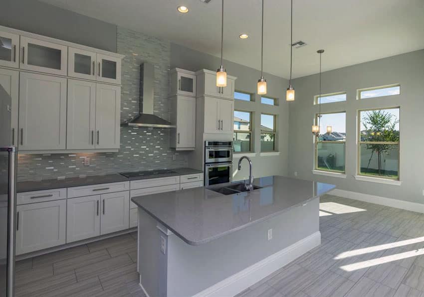 Contemporary kitchen with white cabinets, gray island counter, pendant lighting and gray backsplash