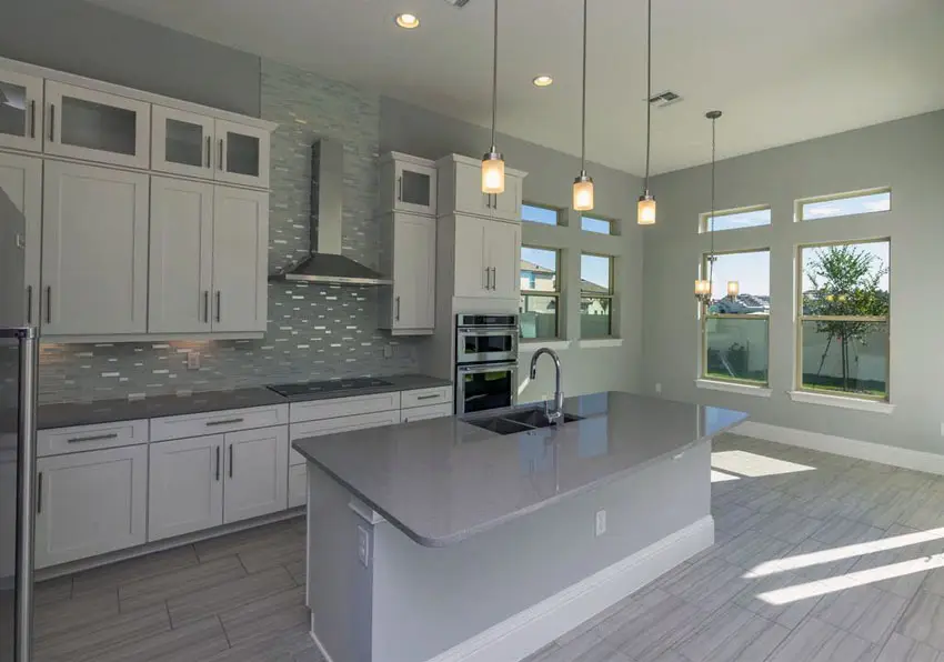 Contemporary kitchen with white cabinets, gray island counter, pendant lighting and gray backsplash