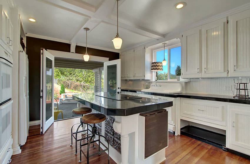 Cottage kitchen with beadboard cabinets wood floors and eat in dining island