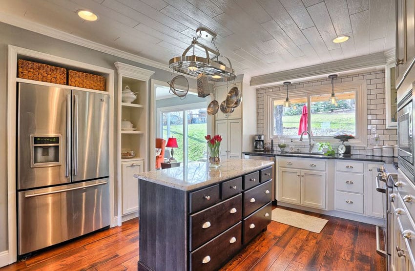 Cottage kitchen with dark brown island, white subway tile backsplash and wood flooring