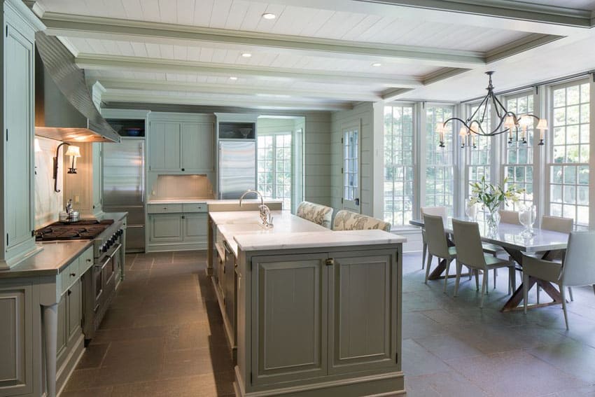 Kitchen with green cabinets, island and white marble countertops and picture windows