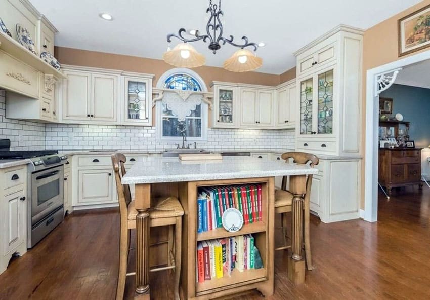 Country kitchen with white raised panel cabinets, wood center island with book storage and classic white subway tile