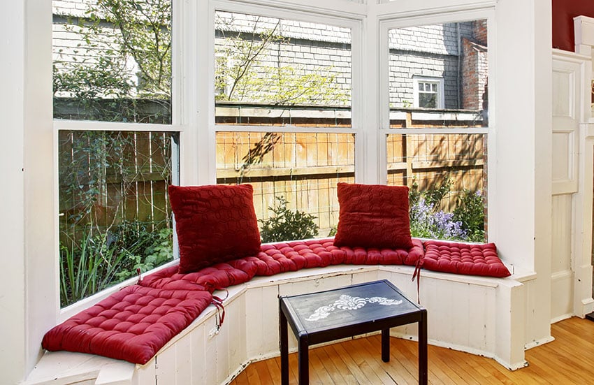 Curved window seat with red cushions