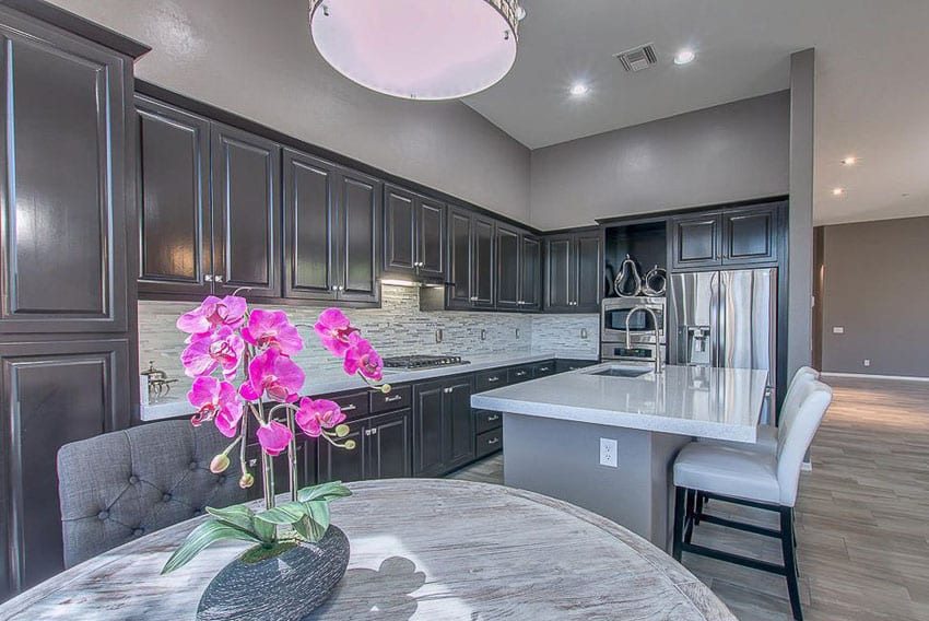 Dark gray kitchen cabinets and gray painted walls and island with white quartz countertop