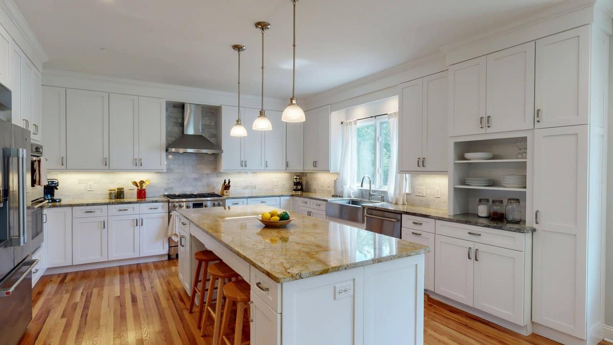 White shaker kitchen with yellow granite island and pale oak plank floors