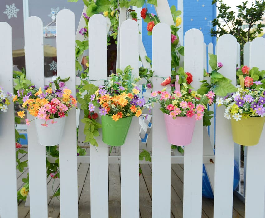 Flower pots hanging from white fence