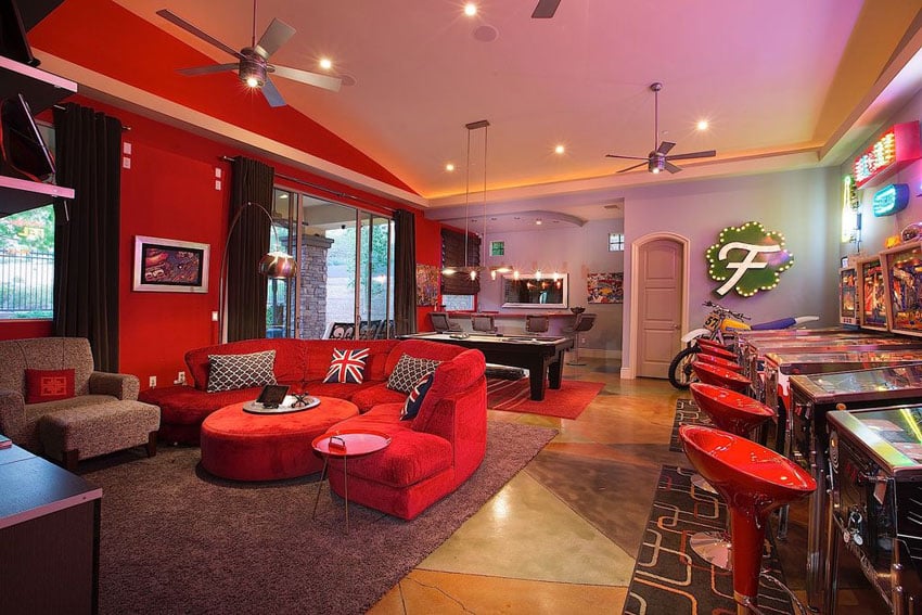 Game room man cave with red furniture, pool table and pinball machines