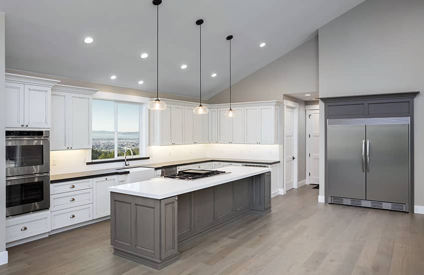 gray and white kitchen with large island pendant lights and vaulted ceiling