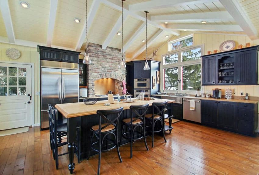 Kitchen with black cabinets with beadboard doors, vaulted ceiling, large island and wood countertop