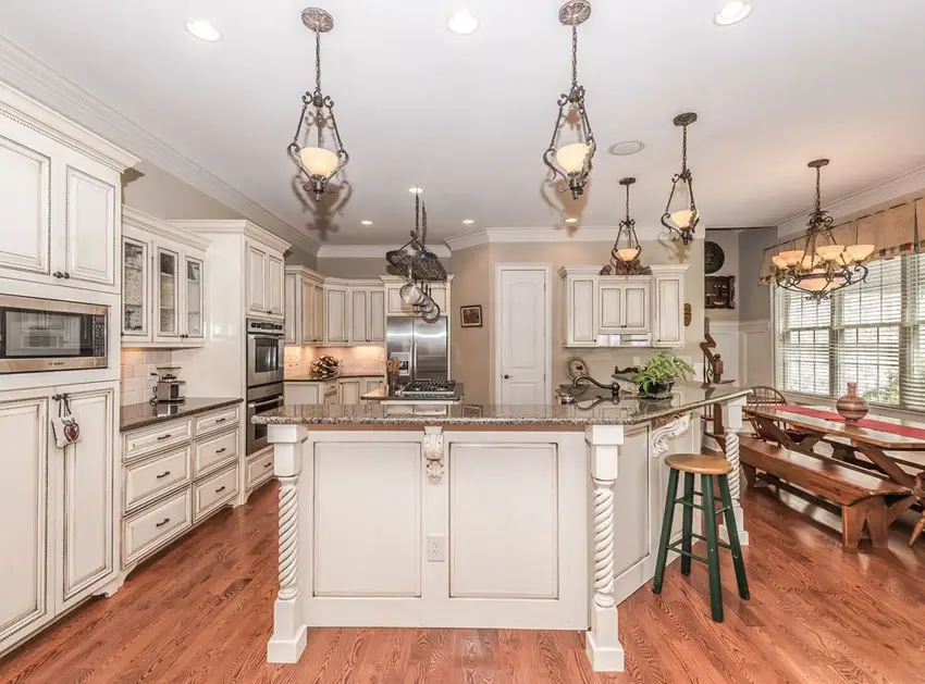 Kitchen with distressed white cabinets with antique door hardware and red oak floors