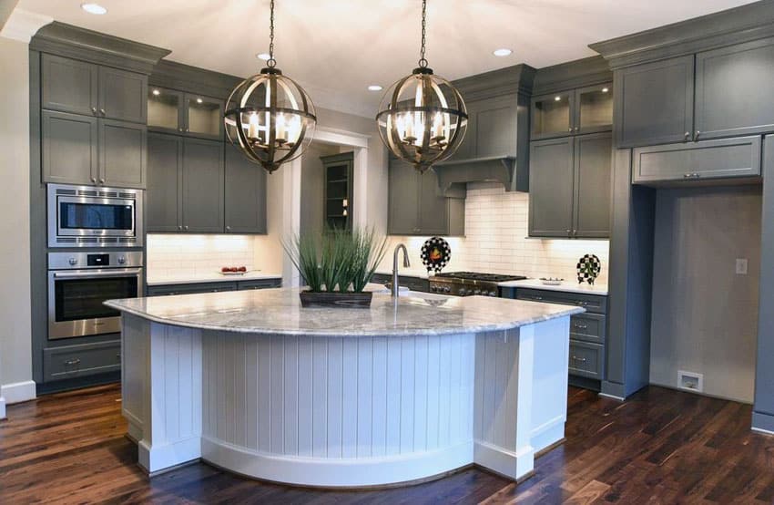 Kitchen with gray cabinets, white island with white subway tile backsplash and globe pendant lights