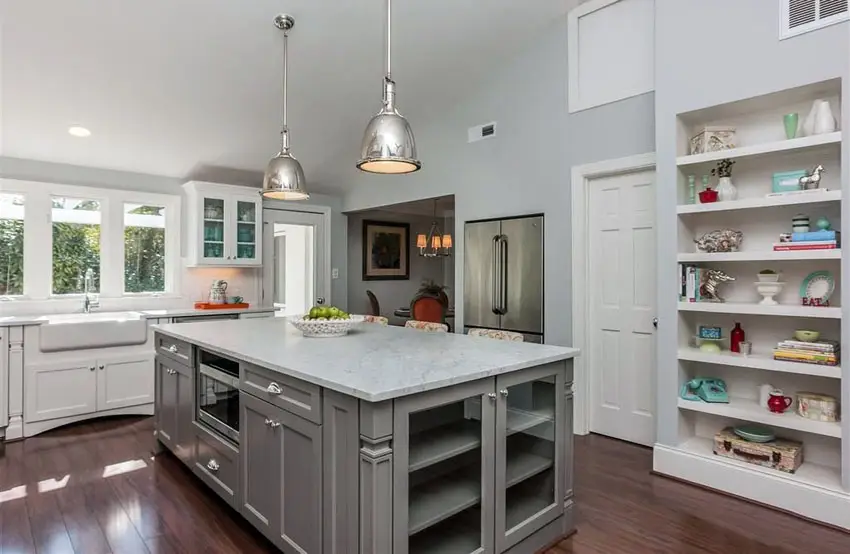 Kitchen with gray island and white cabinets with white marble counters