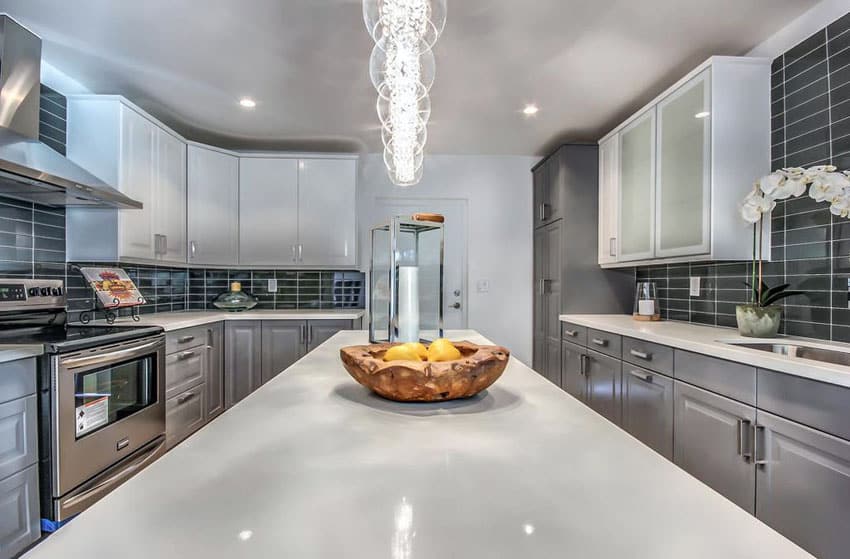 Kitchen with raised gray lower cabinets and white upper cabinets with quartz center counter