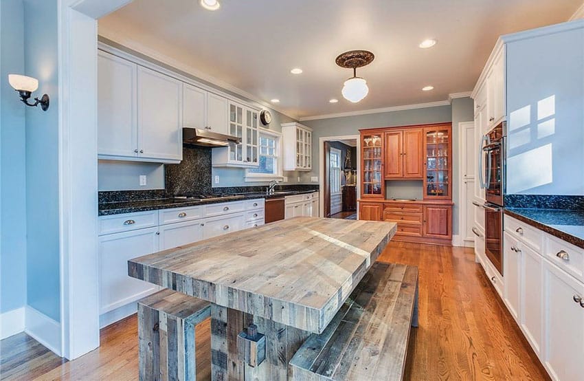 Kitchen with light blue painted walls, white cabinets and rustic wood dining table