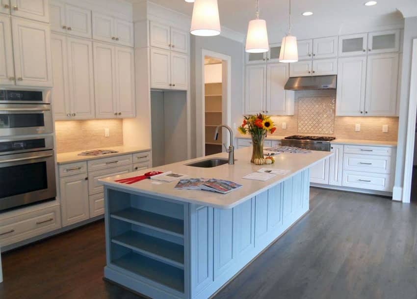 Kitchen with white cabinets, baby blue painted island and mystery white marble