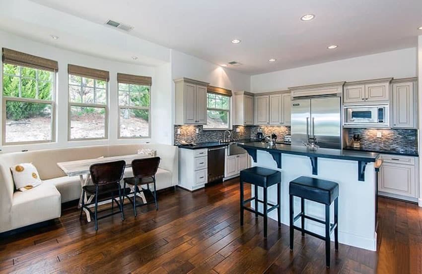 Kitchen with window seat and wood table with black counter breakfast bar