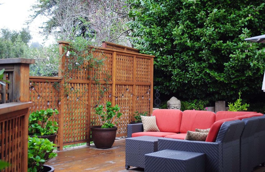 Patio lattice screens with plants and furniture with red cushions