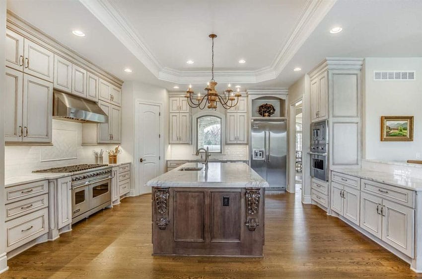 Luxury kitchen with antique white cabinets with glazed fnish, carrara marble counter island and walnut floors